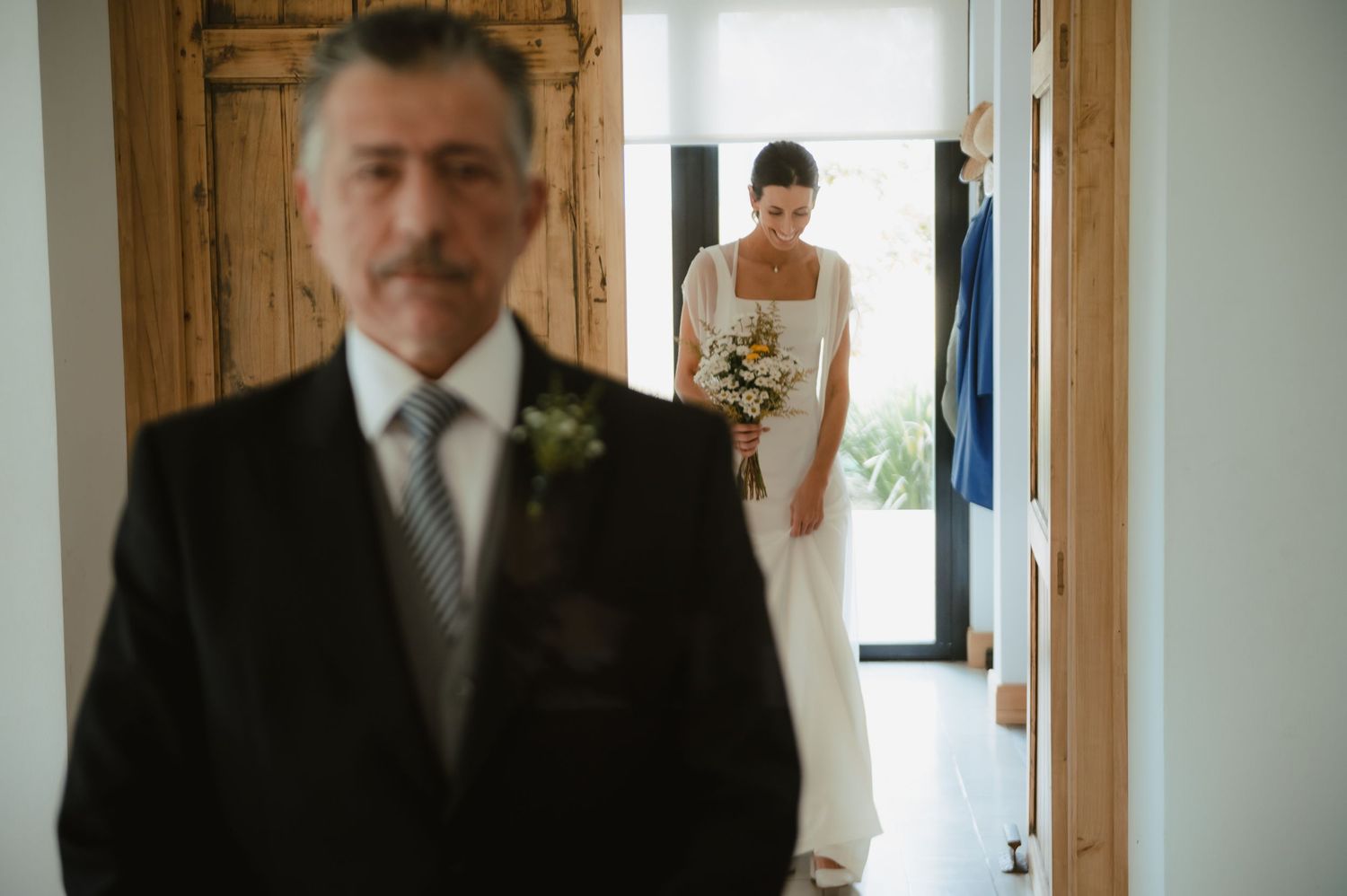 A person gets ready on their wedding day in a rustic wood-paneled room while others help with preparations.