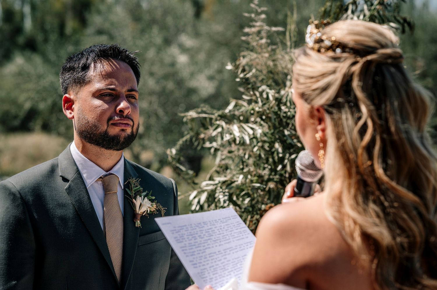 A couple shares an intimate moment during their outdoor wedding ceremony in a lush garden setting.
