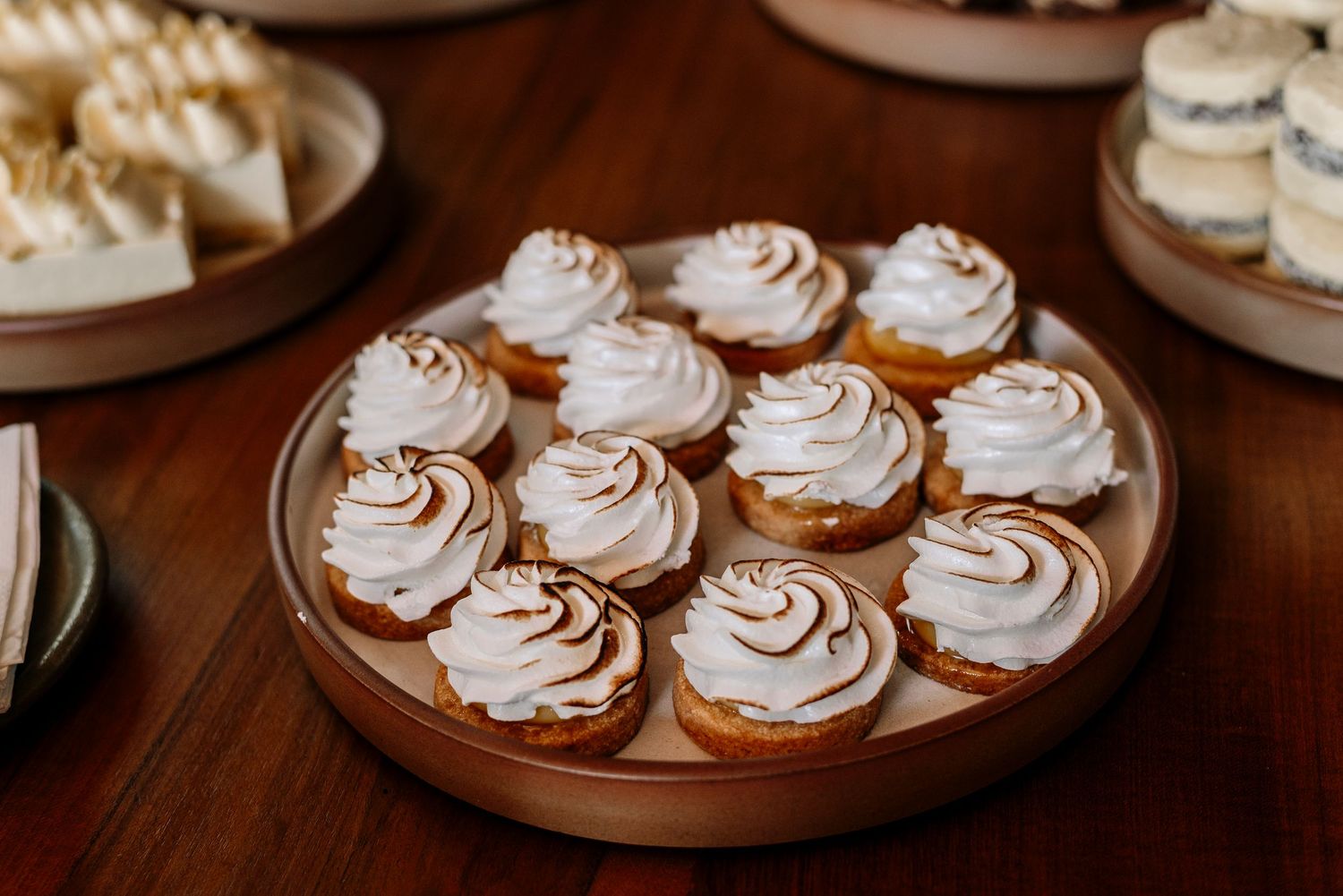 Small chocolate meringue cookies with swirled white frosting arranged on brown plates.