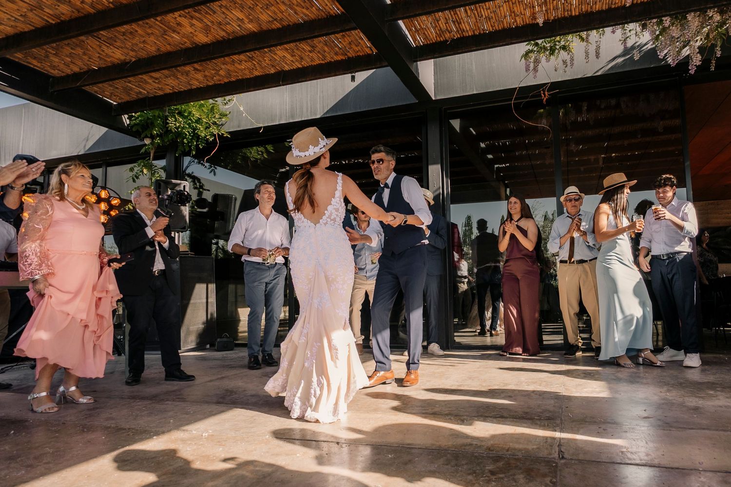 Wedding guests dance and celebrate together on a rustic wooden dance floor during an indoor reception.