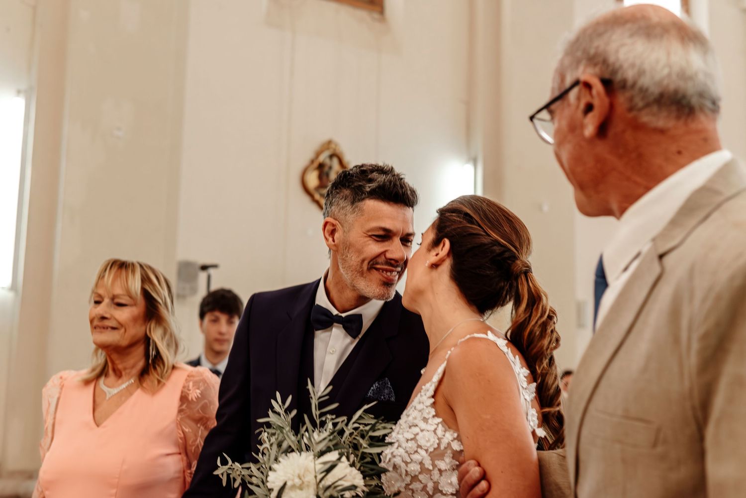 Wedding guests share joyful reactions and emotions during a special moment at an elegant indoor ceremony.