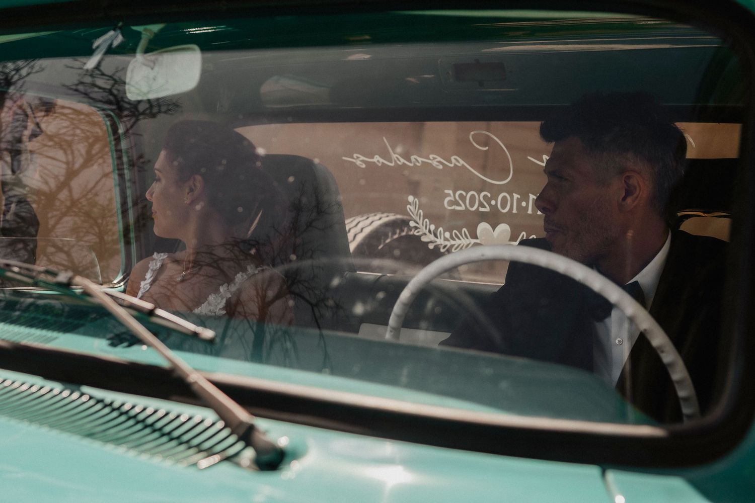 Classic vintage car dashboard and steering wheel details shown through windshield glass with reflections.