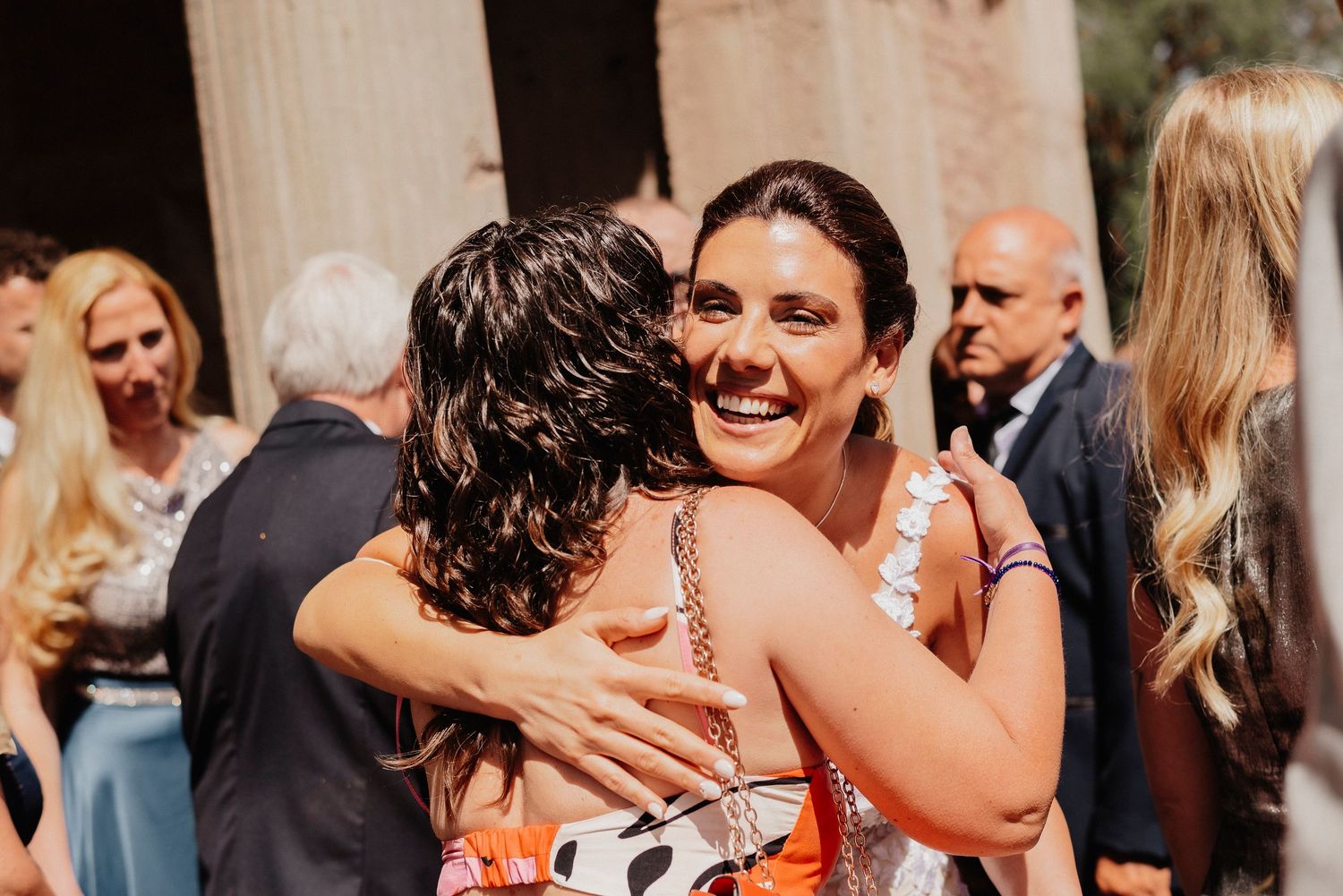 Wedding guests dance and celebrate together at an outdoor reception during a joyful summer celebration.