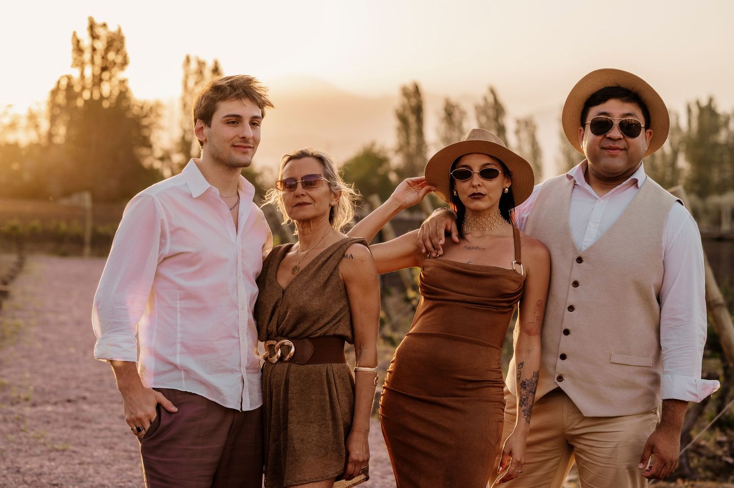 A group in coordinated brown and white outfits poses together during golden hour in a desert setting.