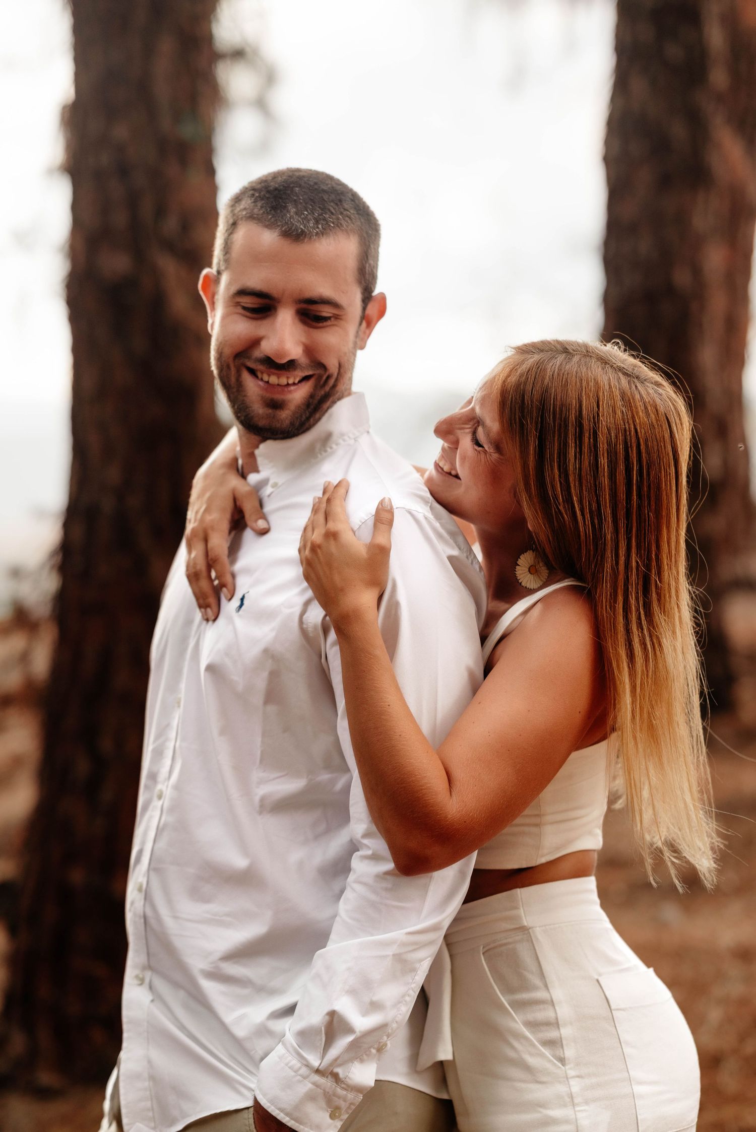 A romantic couple in white outfits share tender moments in a forest setting during a photo session. pre boda in mendoza