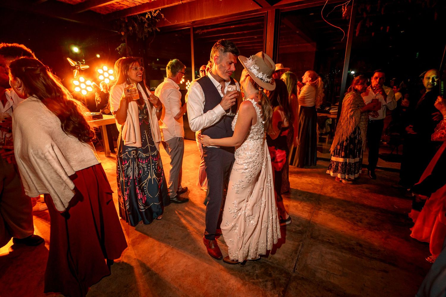 Couples dancing at a rustic wedding reception with warm lighting and sparklers creating a romantic atmosphere.
