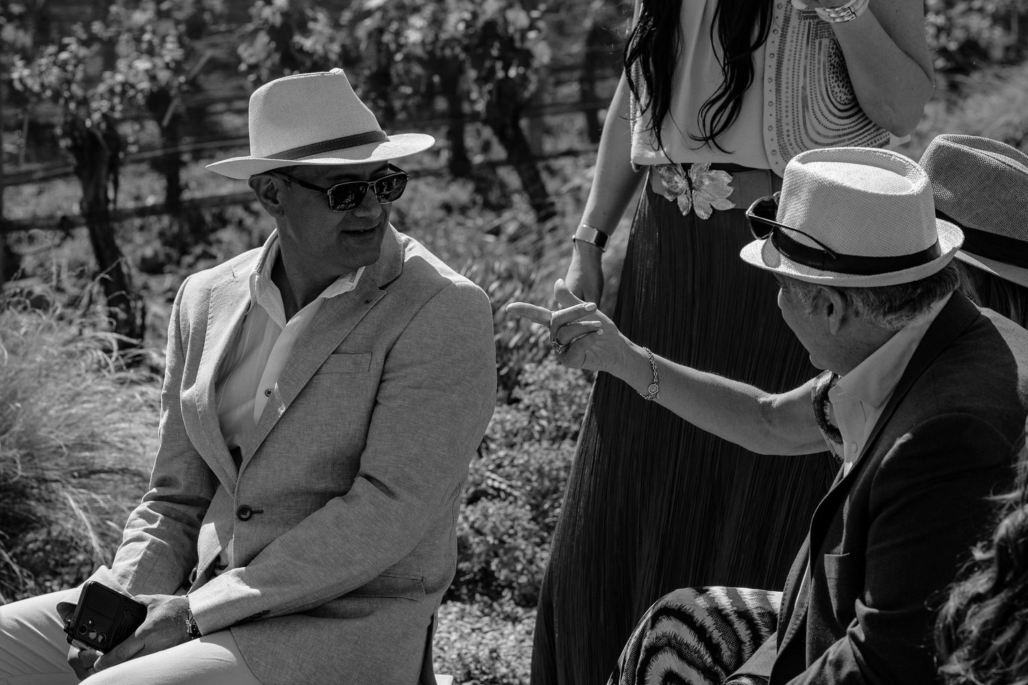 Black and white photographs showing people gathered outdoors in a casual social setting wearing hats and casual attire.