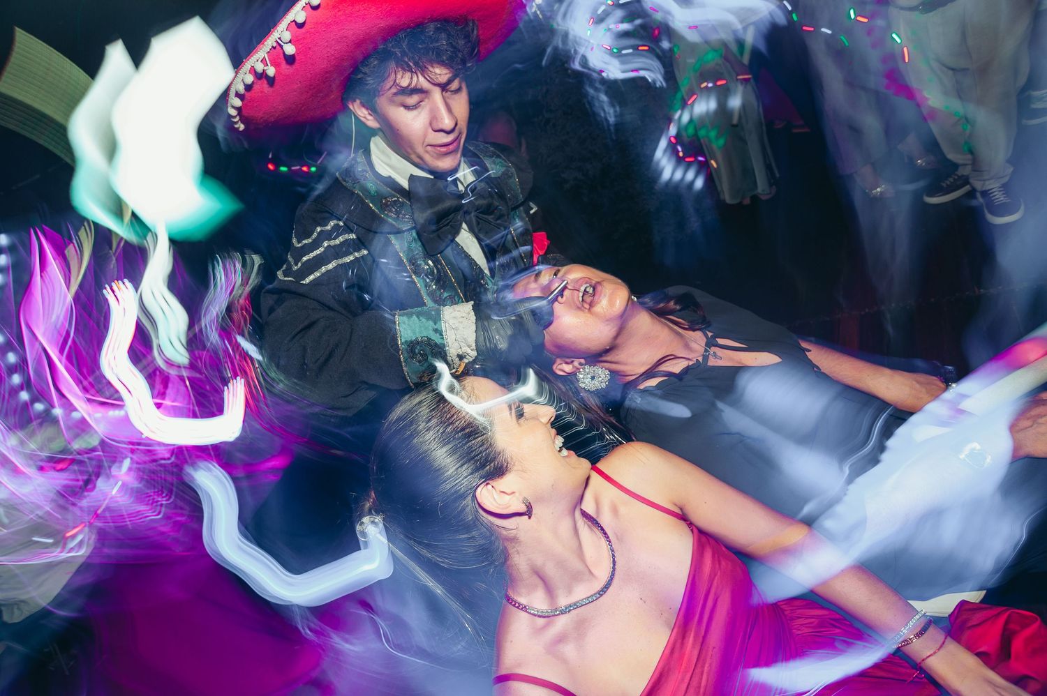 People dancing at a nightclub with colorful purple lighting and fog effects creating an energetic party atmosphere. fotografos de boda