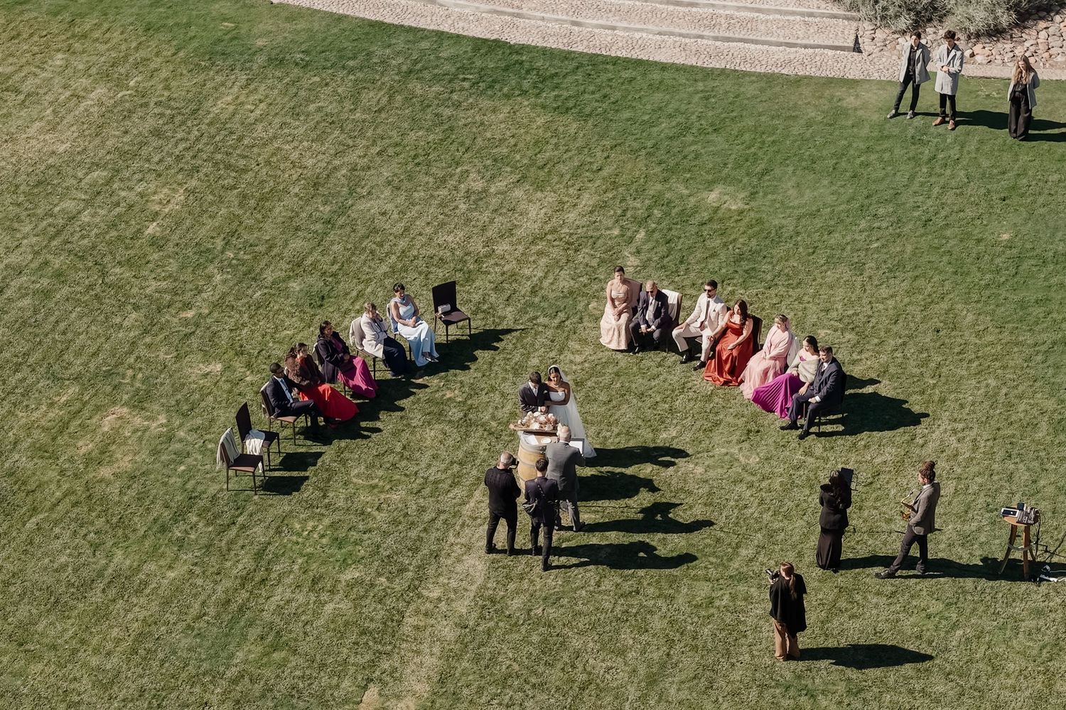 Aerial view of a wedding ceremony with guests seated in a semicircle on a lush green lawn outdoors. fotógrafos de boda Mendoza