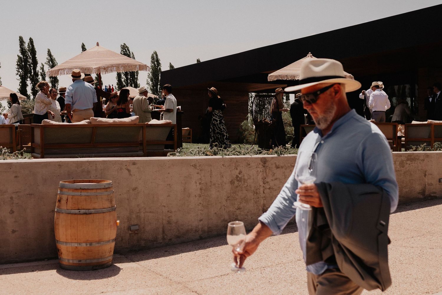 Wine barrels and guests enjoying an outdoor tasting experience at a rustic winery patio.
