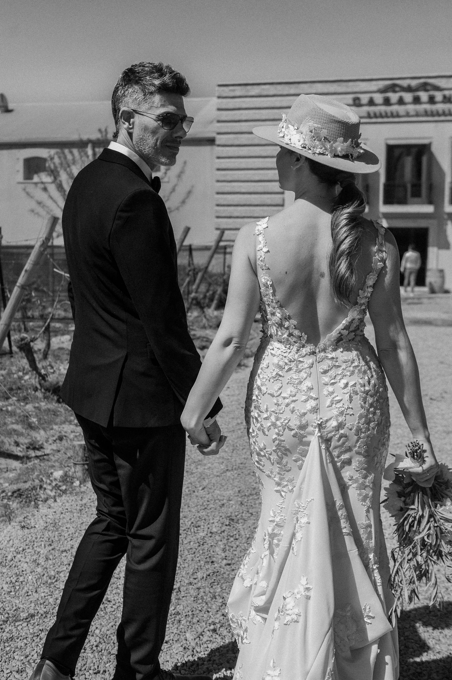 Black and white wedding photo series showing a couple walking together outdoors in formal attire.