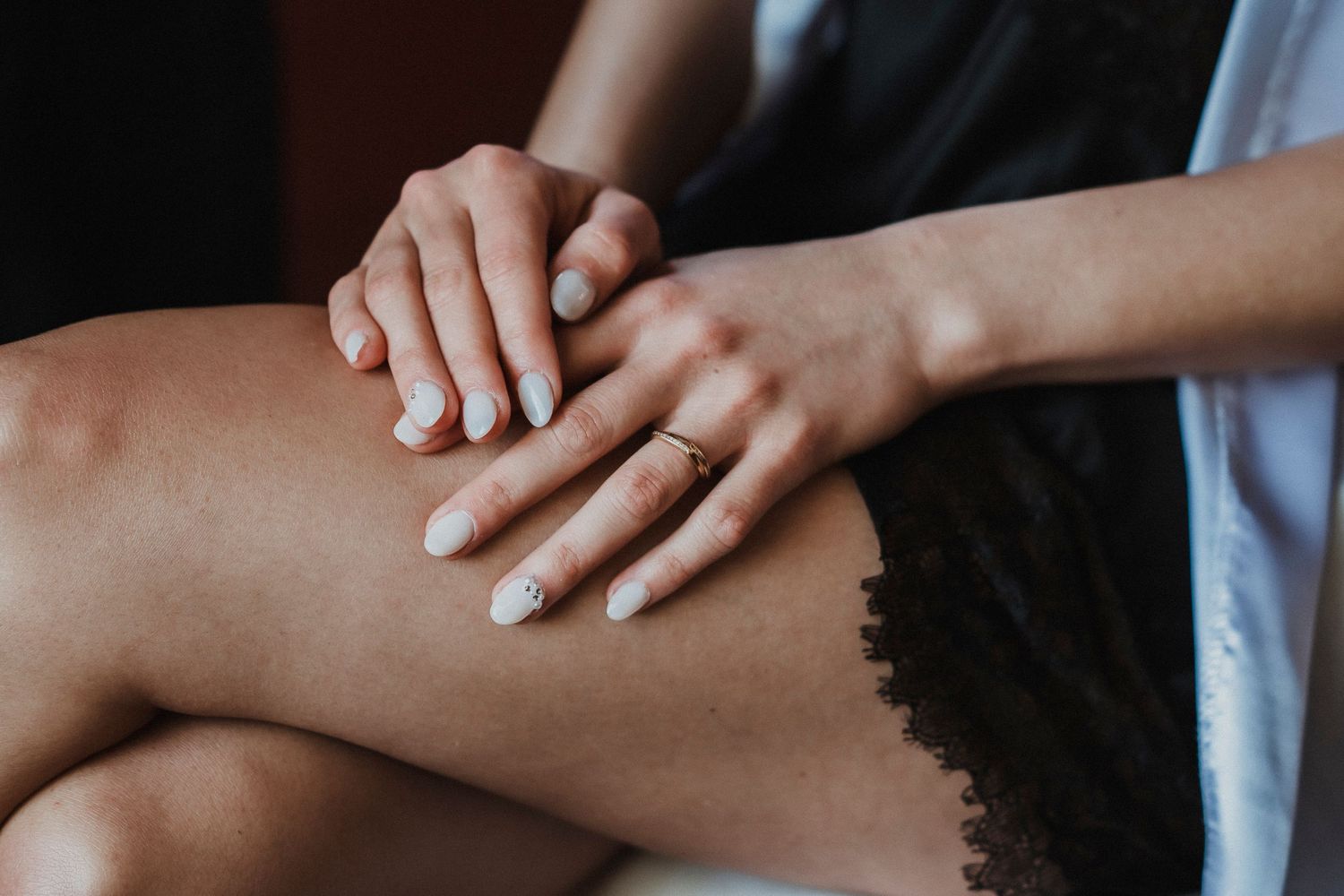 Close-up view of hands gently touching and caressing each other against a dark background.