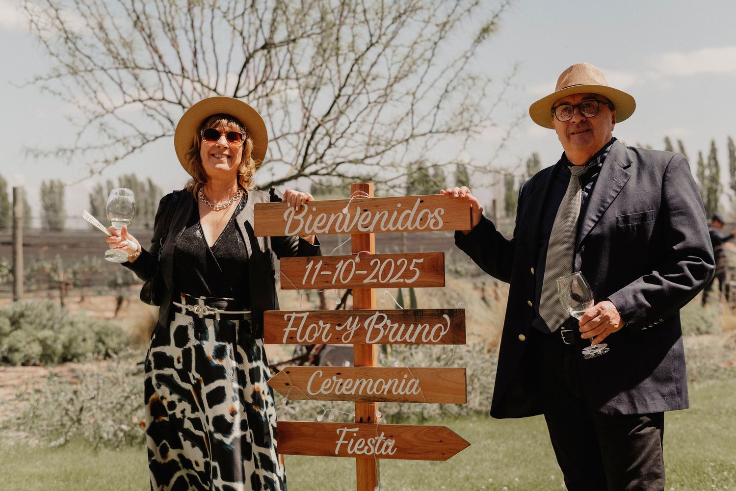 Rustic wooden wedding directional signs point guests to different locations at an outdoor ceremony venue.