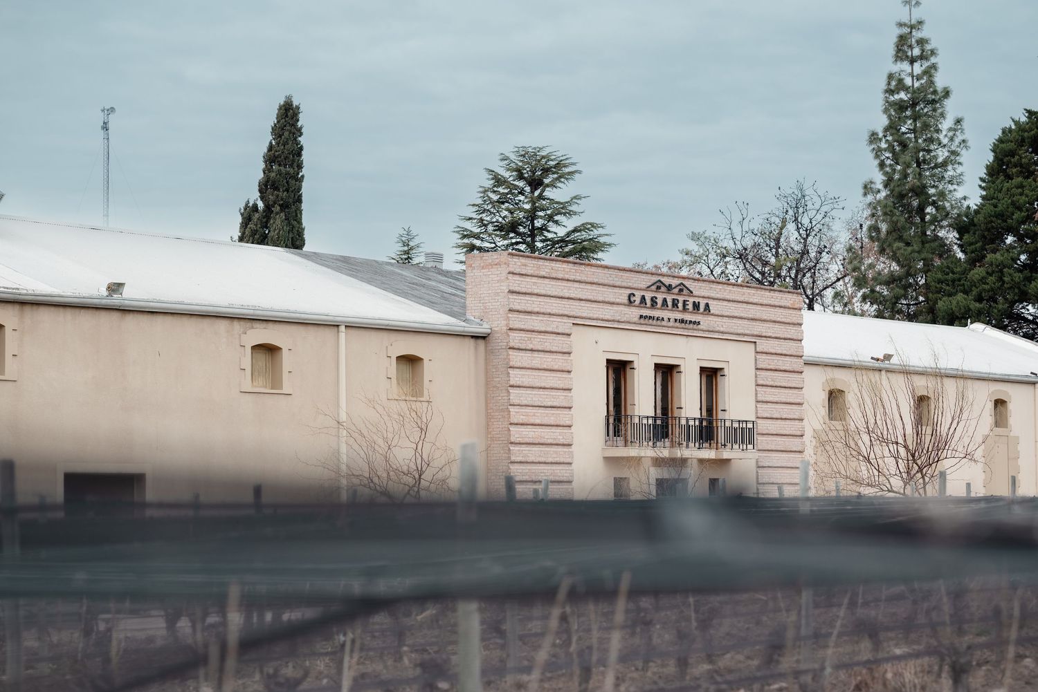 Vintage art deco style entrance to Merope winery building with white walls and arched windows under overcast sky.