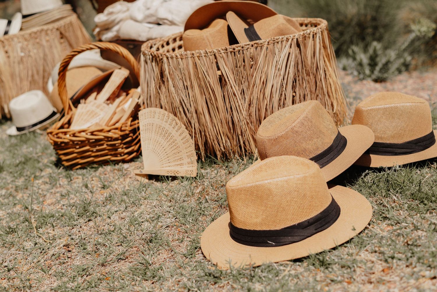 A collection of tan straw hats arranged on the ground in a rustic outdoor setting.