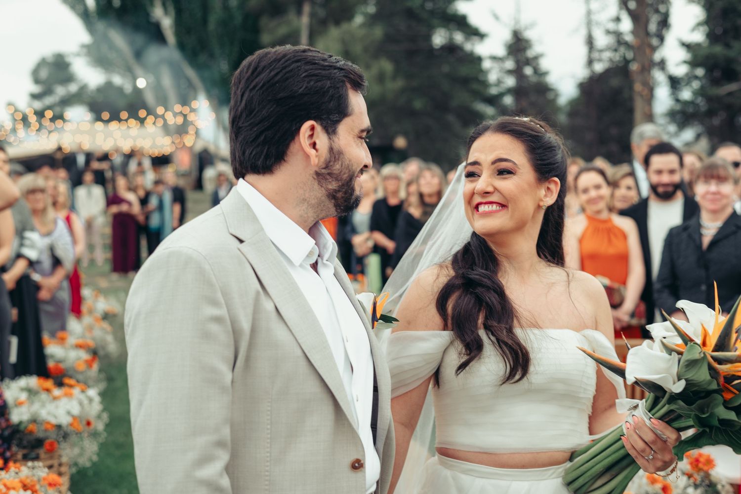 A joyful outdoor wedding celebration with the newlyweds sharing a happy moment surrounded by guests and garden flowers.