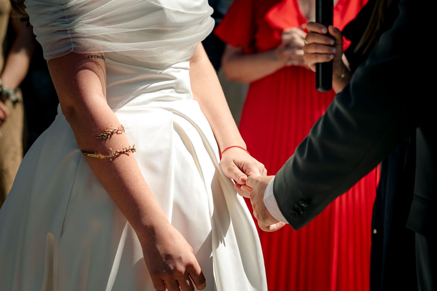 Wedding guests in red dresses stand with others in white gowns during an elegant celebration.