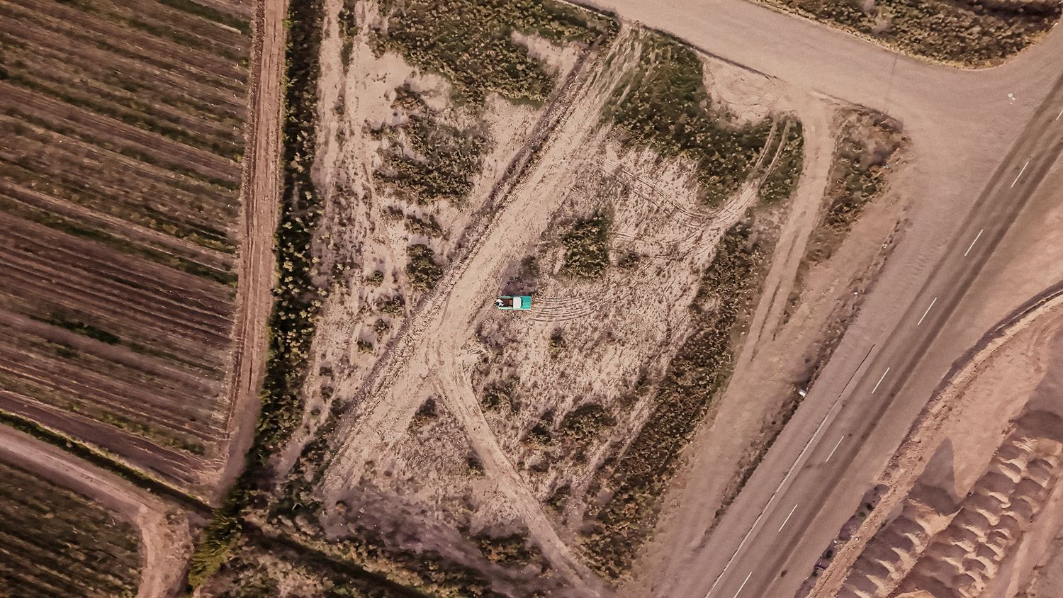 Aerial view of dirt roads intersecting in a rural landscape with plowed fields and barren terrain.