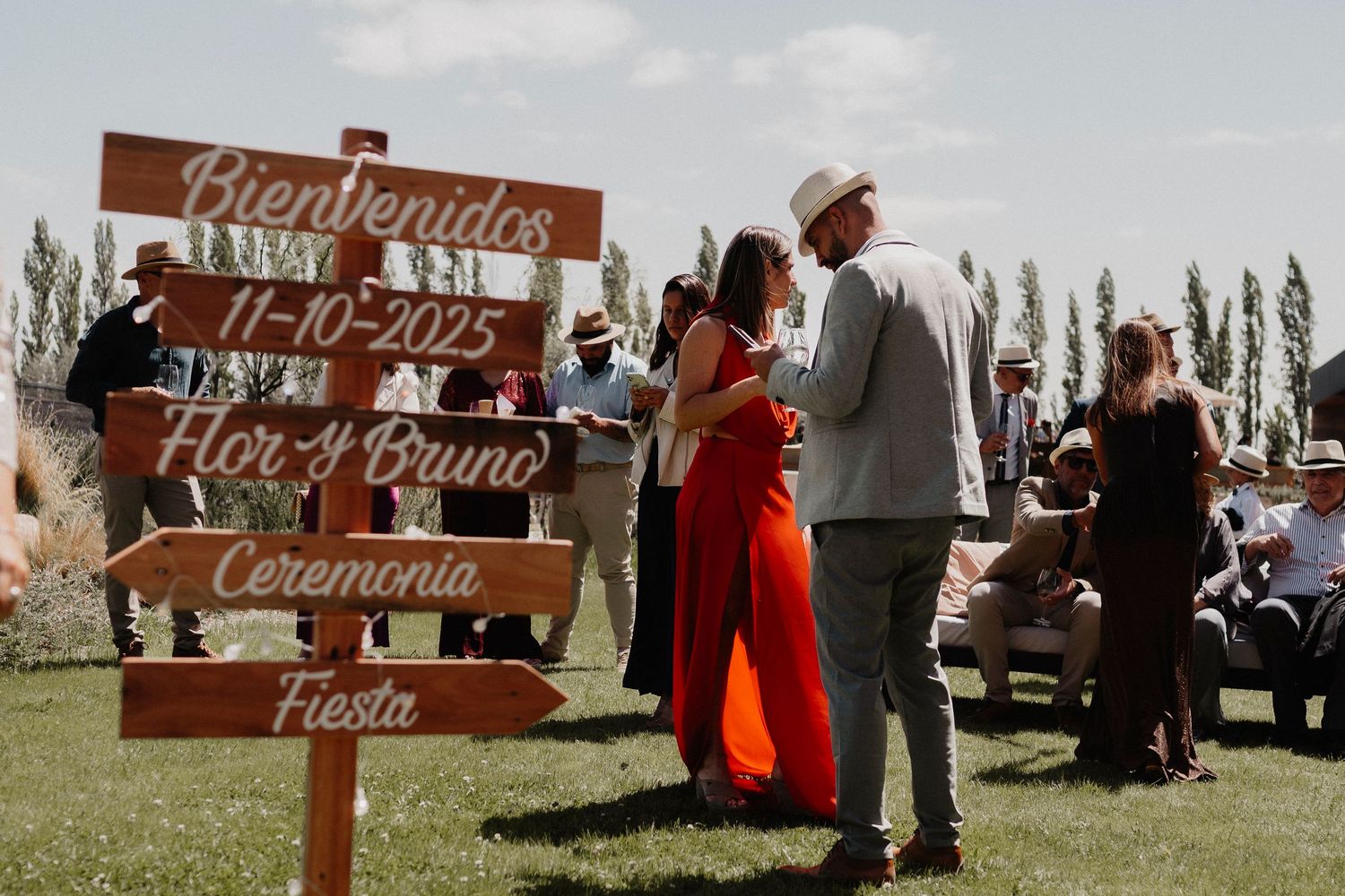 Rustic wooden welcome signs with Spanish text decorate an outdoor event venue.