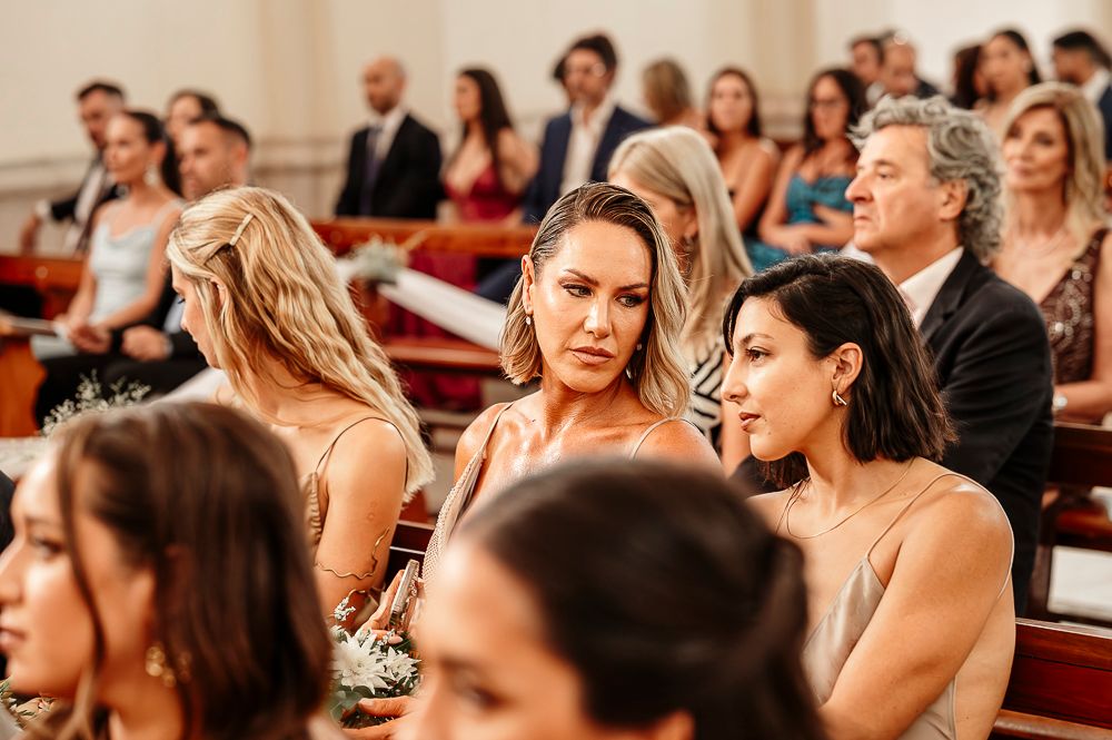Wedding guests seated in church pews look to the side during an emotional ceremony moment. wedding in mendoza