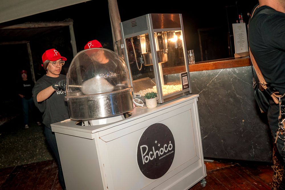 A cotton candy machine being operated at an outdoor nighttime event with glowing lights in the background. wedding in mendoza