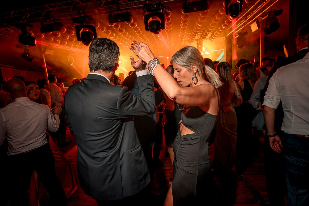 A group of people dancing at a lively party with warm orange lighting and a crowded dance floor. wedding in mendoza