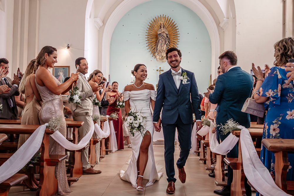 Wedding ceremony guests applaud in a bright church with pale blue walls and ornate decor. wedding in mendoza