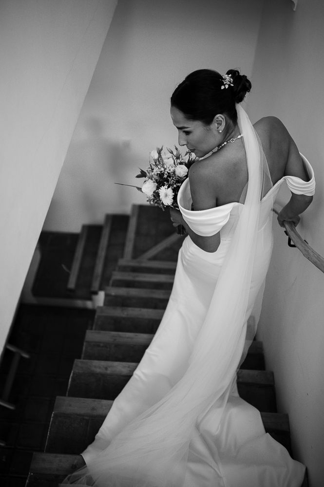 A black and white photo sequence showing a bride in a white wedding dress walking down stairs in an elegant setting. wedding in mendoza