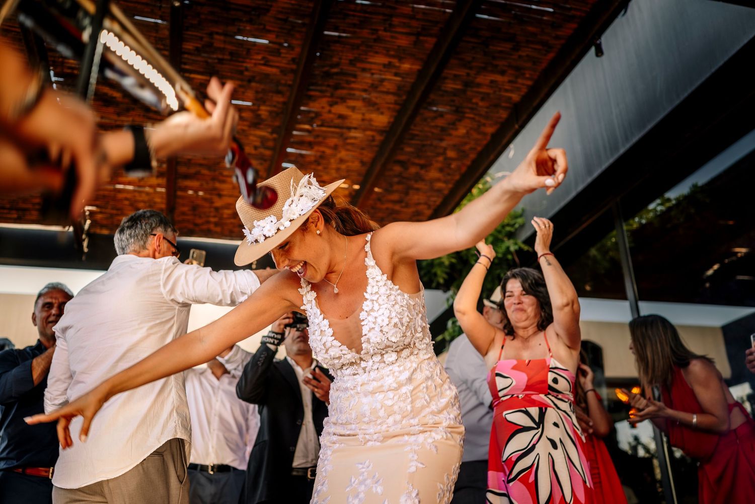 Wedding guests dance and celebrate on a dimly lit dance floor during a lively reception party.