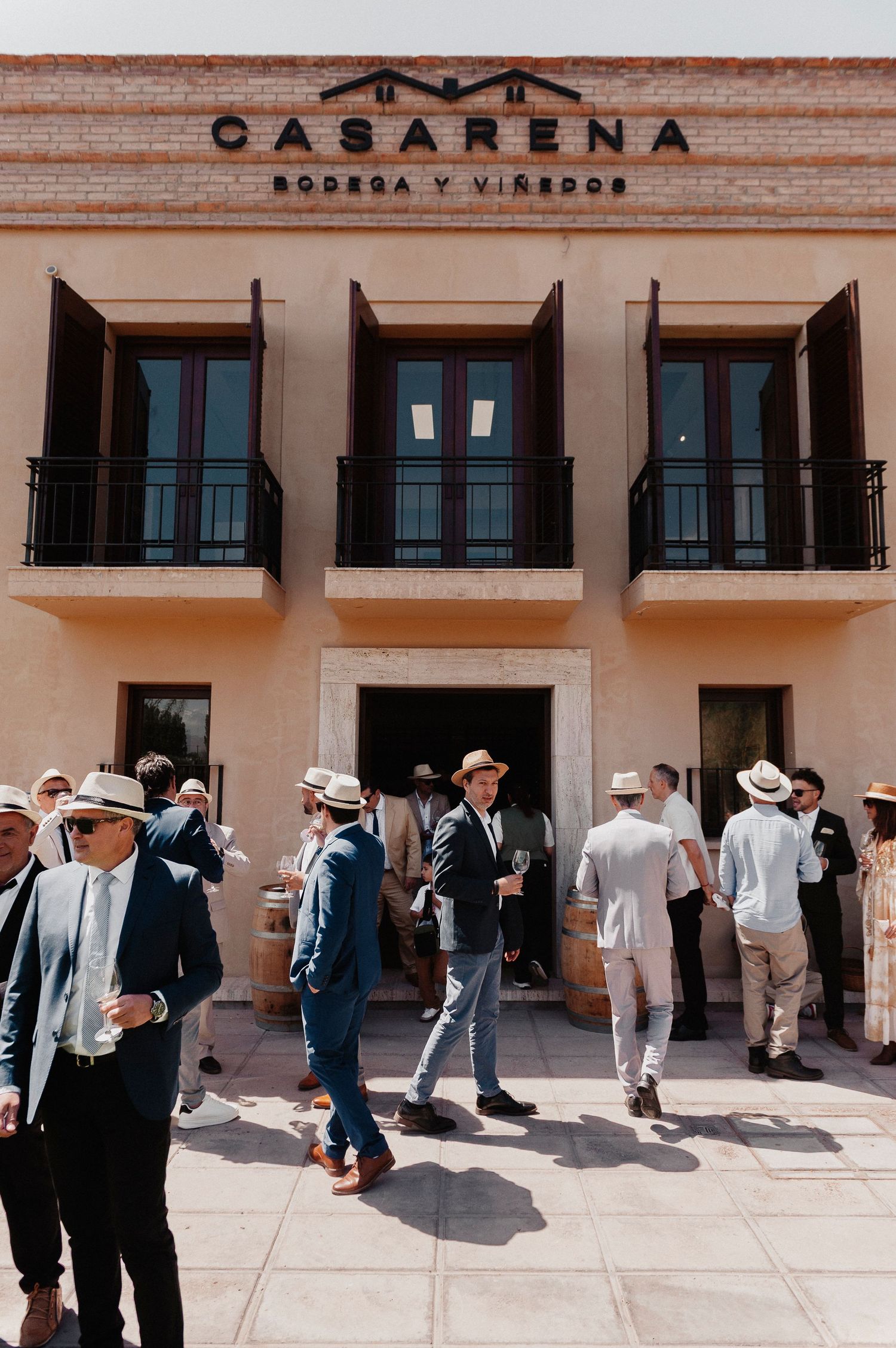 A crowd gathers outside the Casarena winery building with its name displayed prominently on the beige facade.