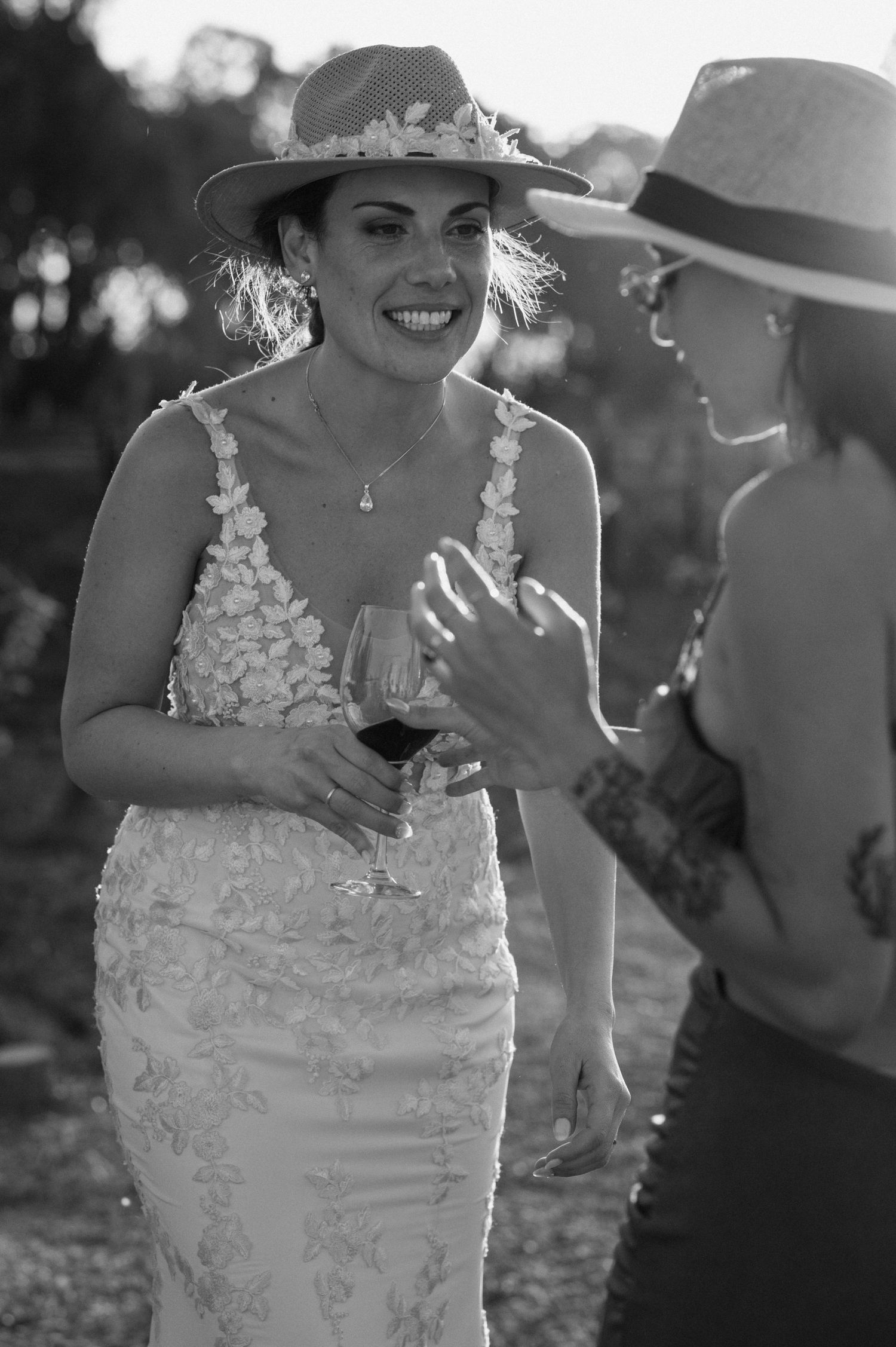 A joyful moment captured in black and white as a bride in a lace dress shares laughter during an outdoor celebration.