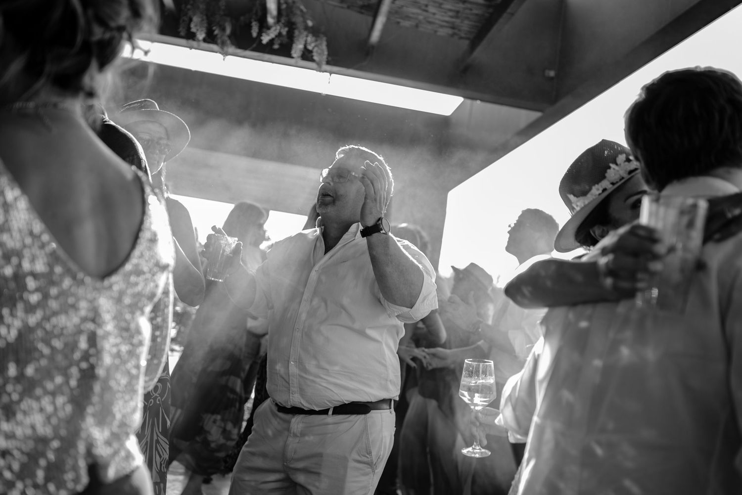 A lively crowd dances and socializes at a dimly lit nightclub with atmospheric lighting and smoke effects.