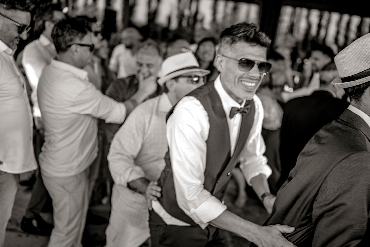 A group of dancers performing at an outdoor event with people watching and dancing together in a celebratory atmosphere.