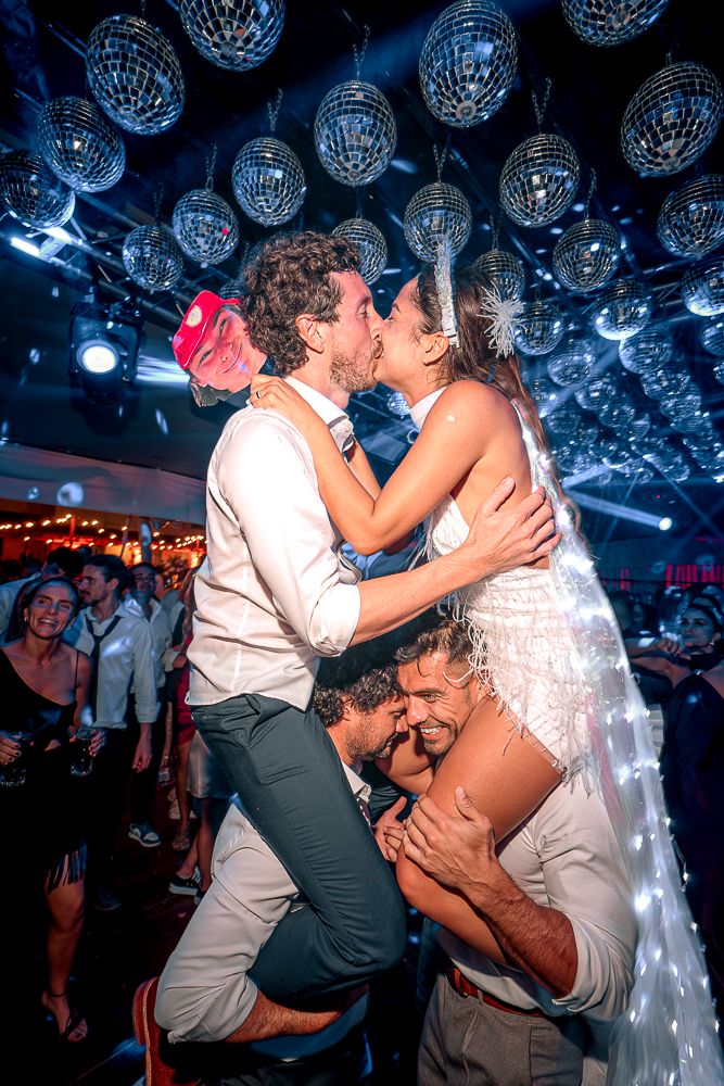 Couple sharing a romantic kiss under blue disco balls at a nightclub wedding celebration.
