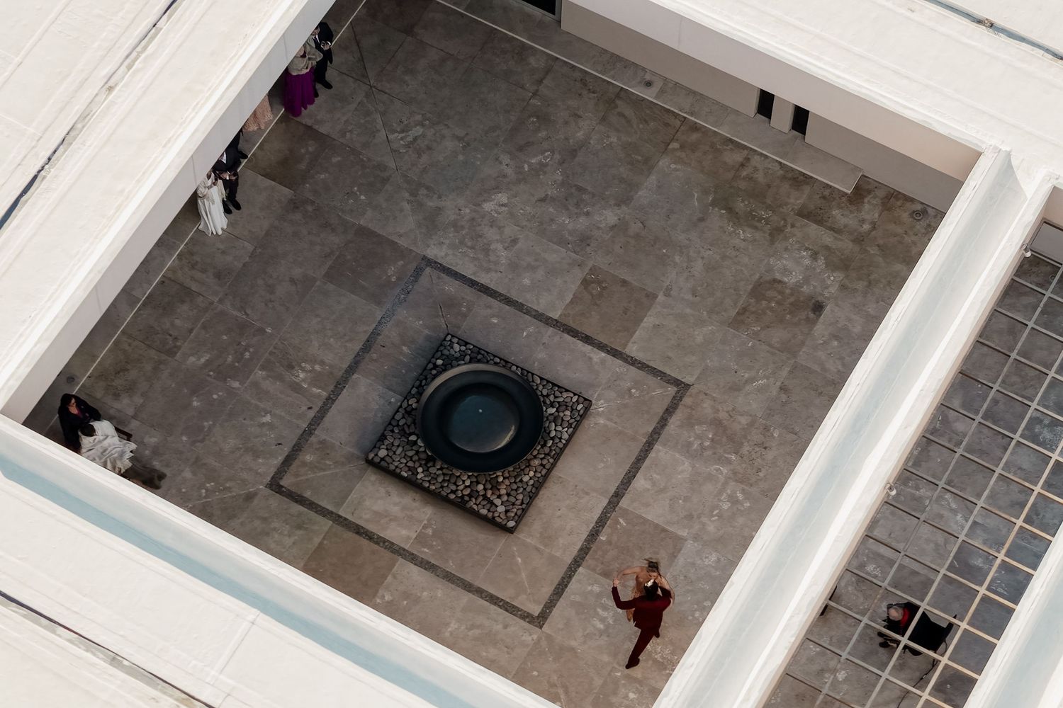 Aerial view of a courtyard with a large decorative bowl centerpiece, surrounded by marble flooring and visitors. fotógrafos de boda Mendoza