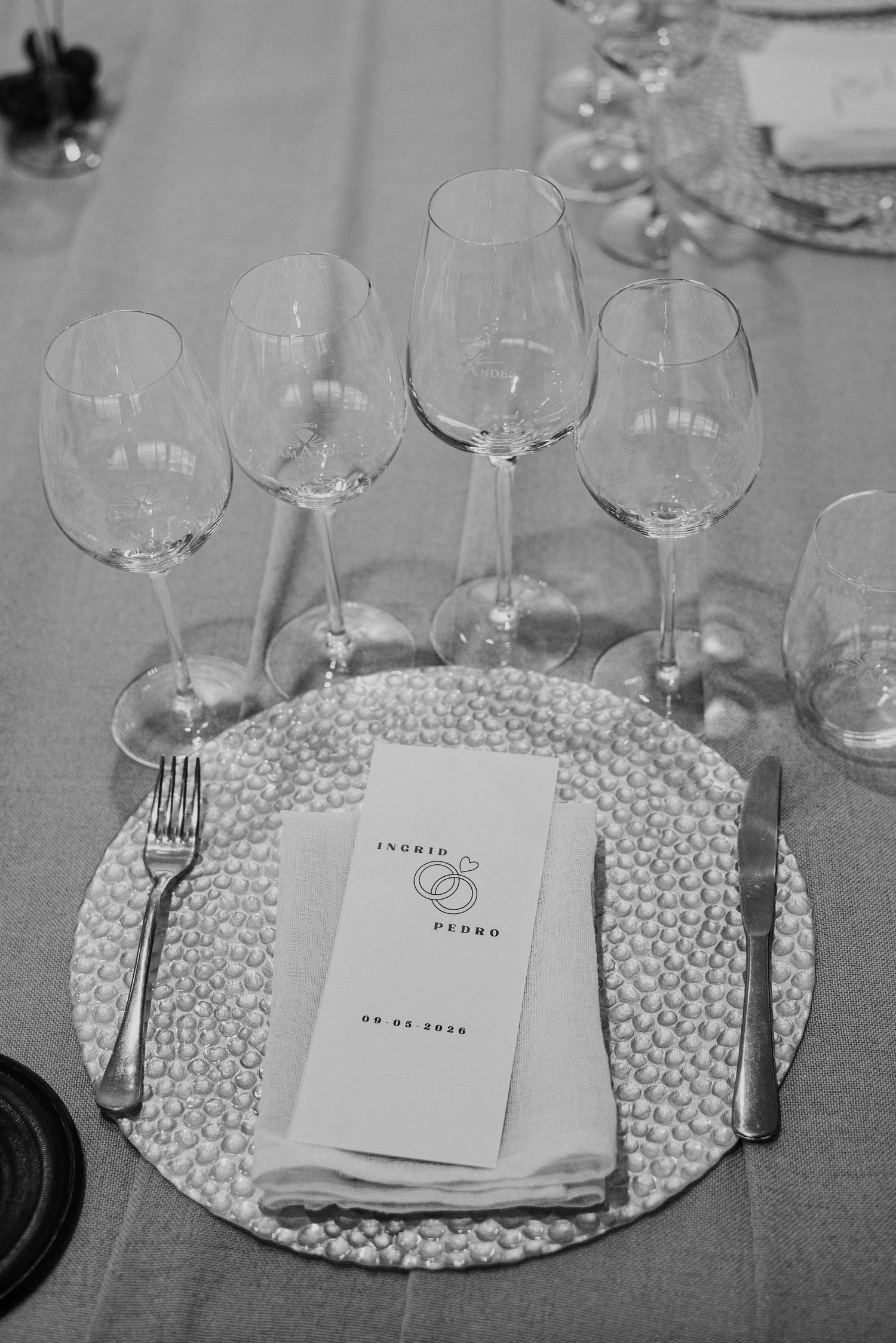 Black and white wedding place setting with wine glasses, decorative charger plate, and personalized menu card for Ingrid and Pedro.