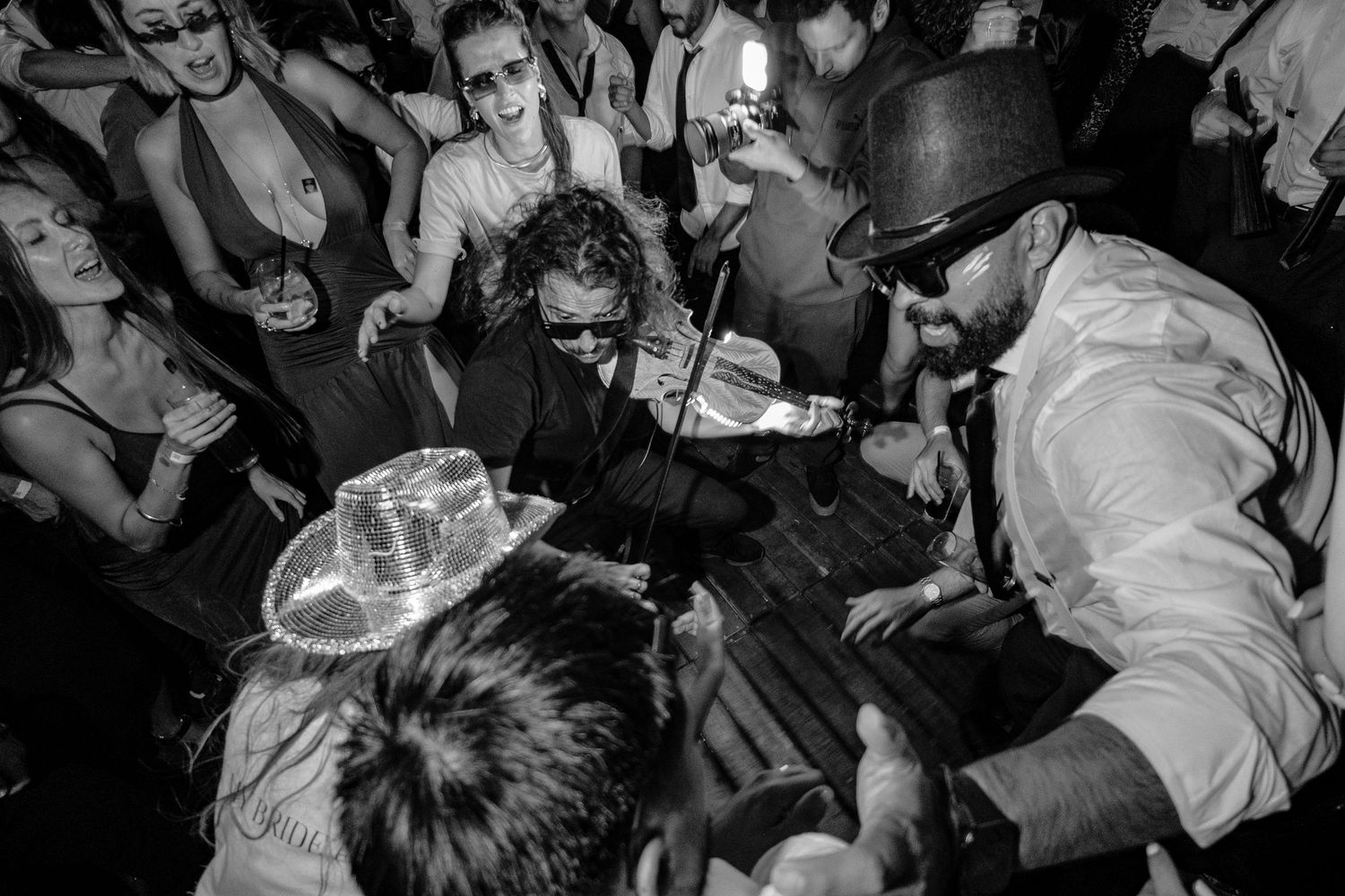 A crowded dance floor at a nightclub with people dancing and moving to the music in a dimly lit space.