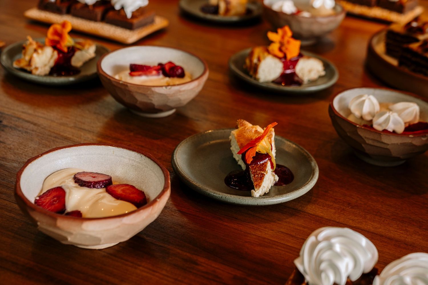 Elegant dessert plates arranged on a wooden table with delicate pastries and cream garnishes.
