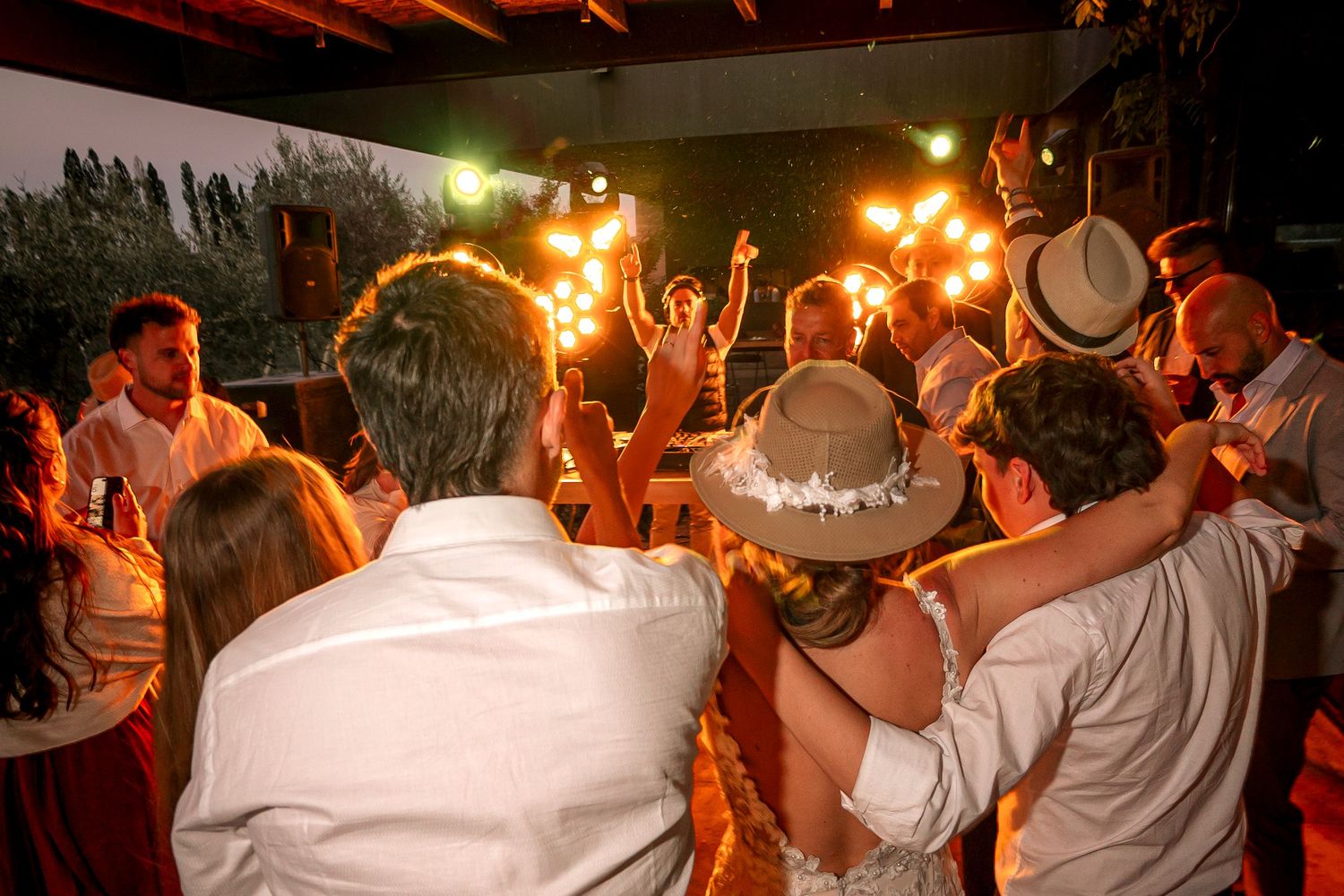 A group of people dance in a line at a celebration event with warm lighting and festive atmosphere.