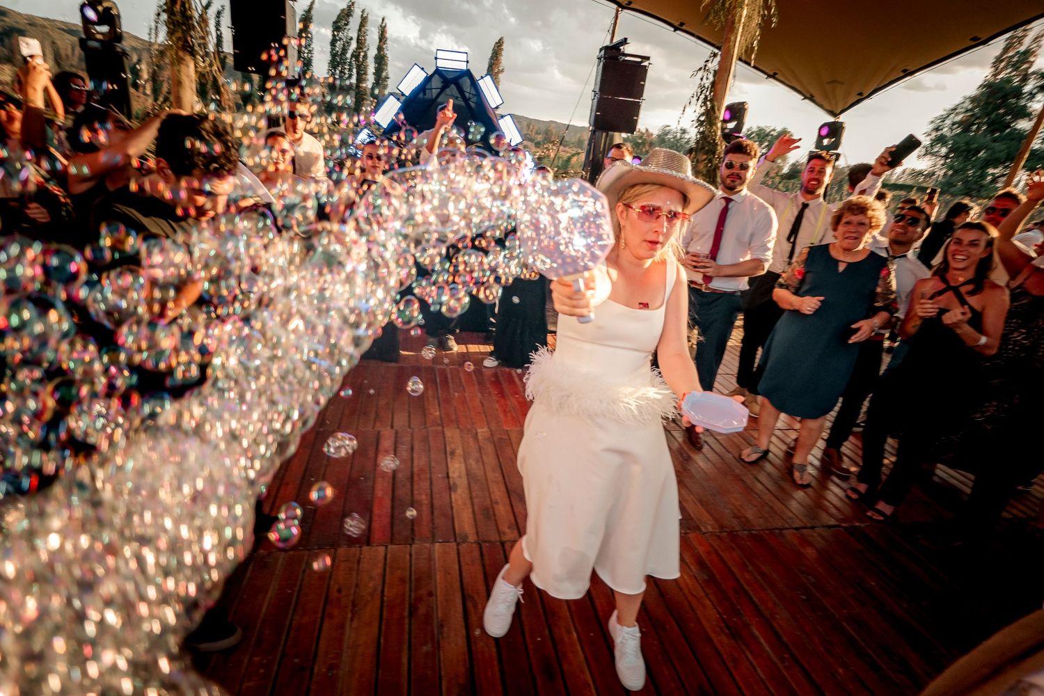 A bride in a white dress dances under sparkling lights on a wooden dance floor during a wedding reception. fotografos de boda en mendoza