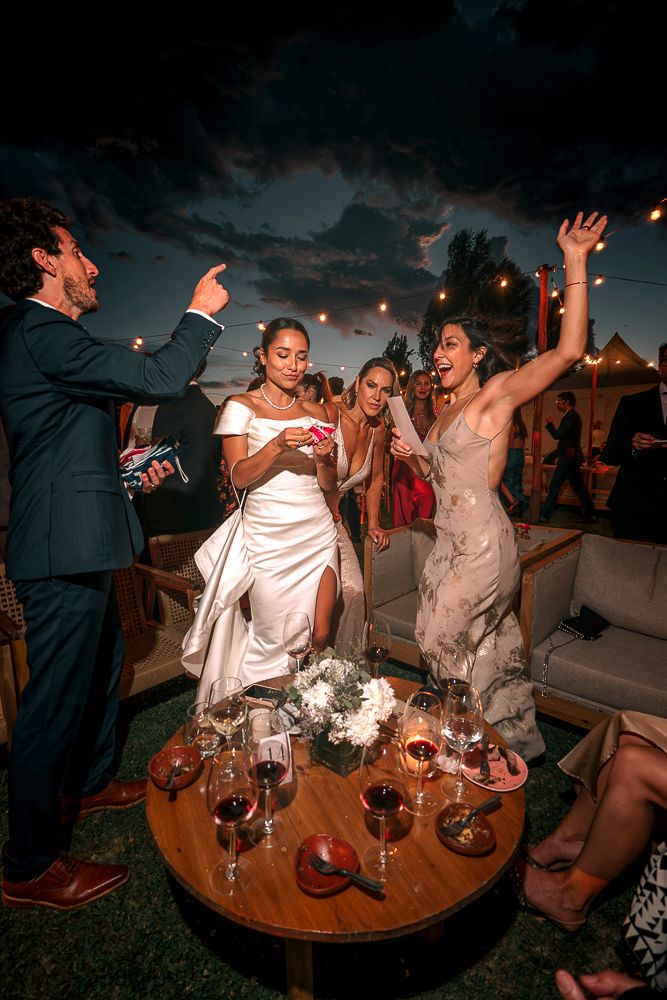 Wedding guests dancing and celebrating at an outdoor evening reception with wine glasses on a round table. wedding in mendoza