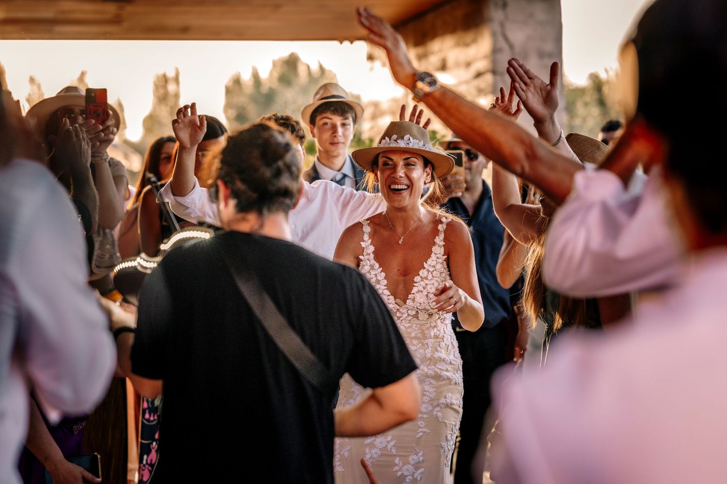 Wedding guests dance and celebrate together on a crowded dance floor at an indoor reception venue.