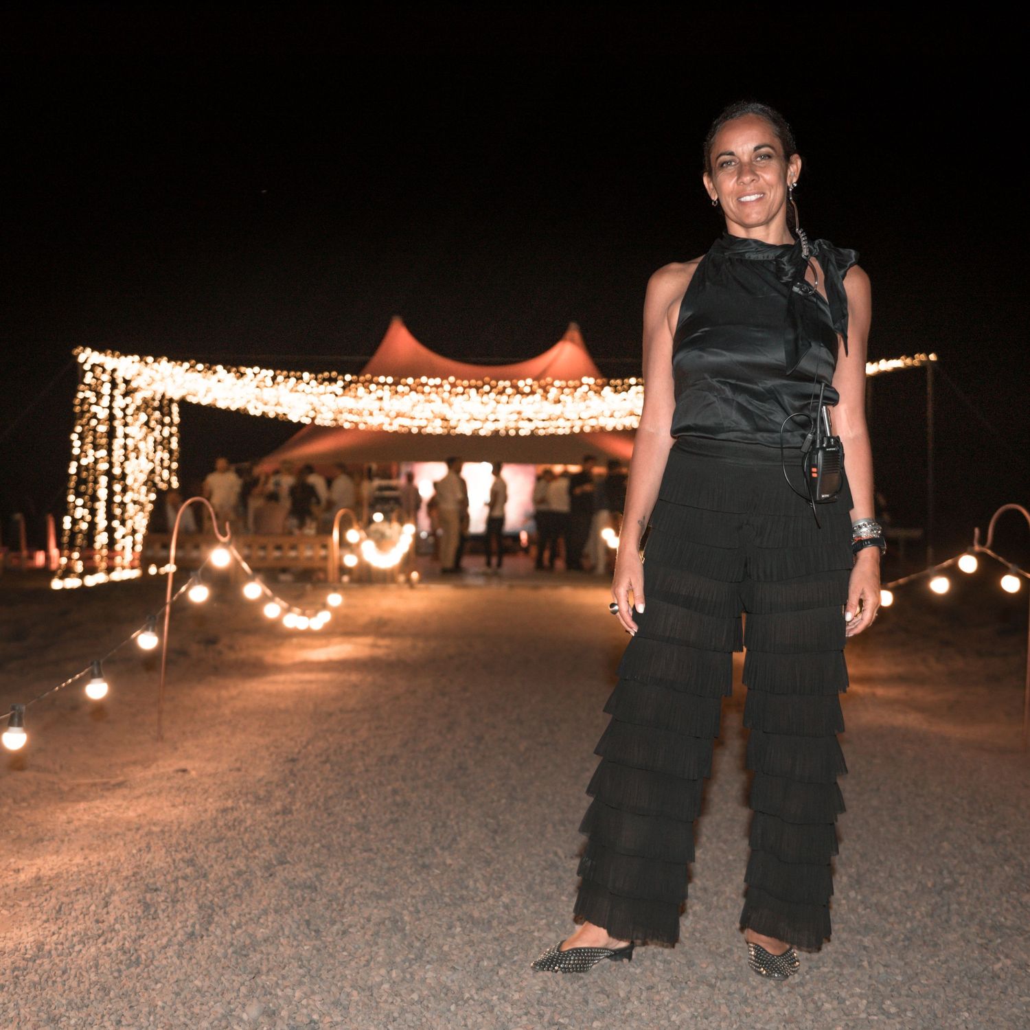 An elegant party scene at night with glowing string lights decorating a tent and pathway in a desert setting.