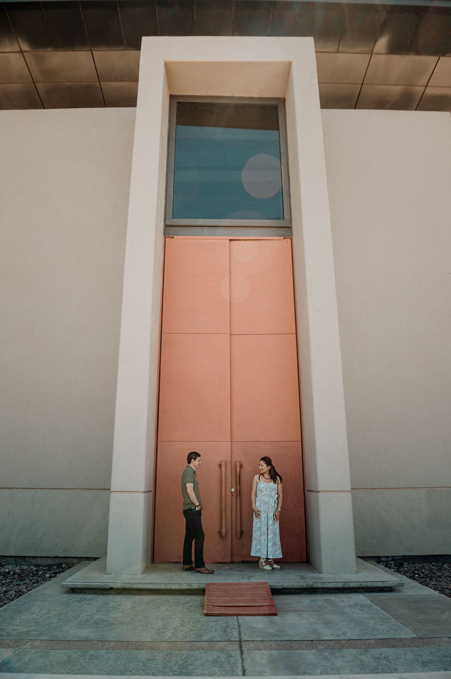 Couple standing in front of tall pink and blue architectural doorway.