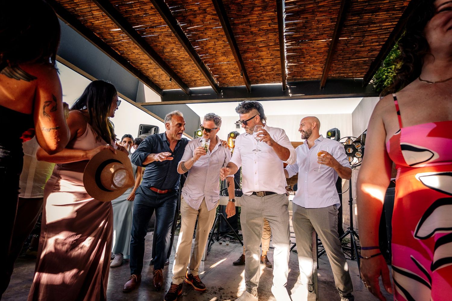People dancing together under a rustic wooden ceiling at a festive celebration event.