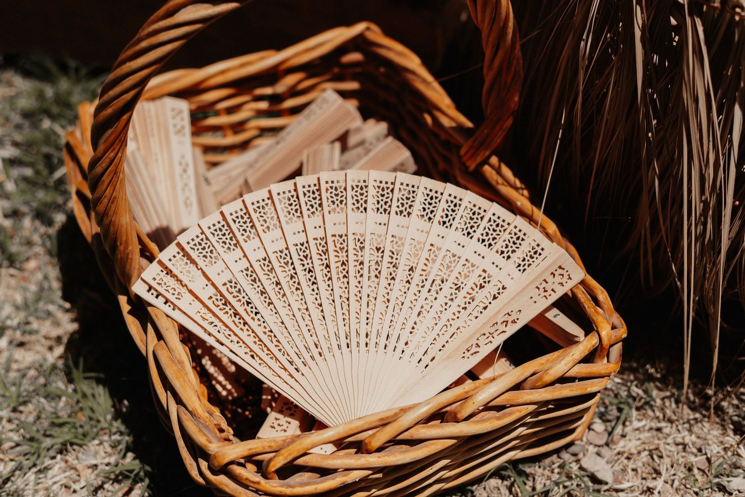 Delicate white folding fans with intricate carved patterns arranged artistically on rustic wooden surface.