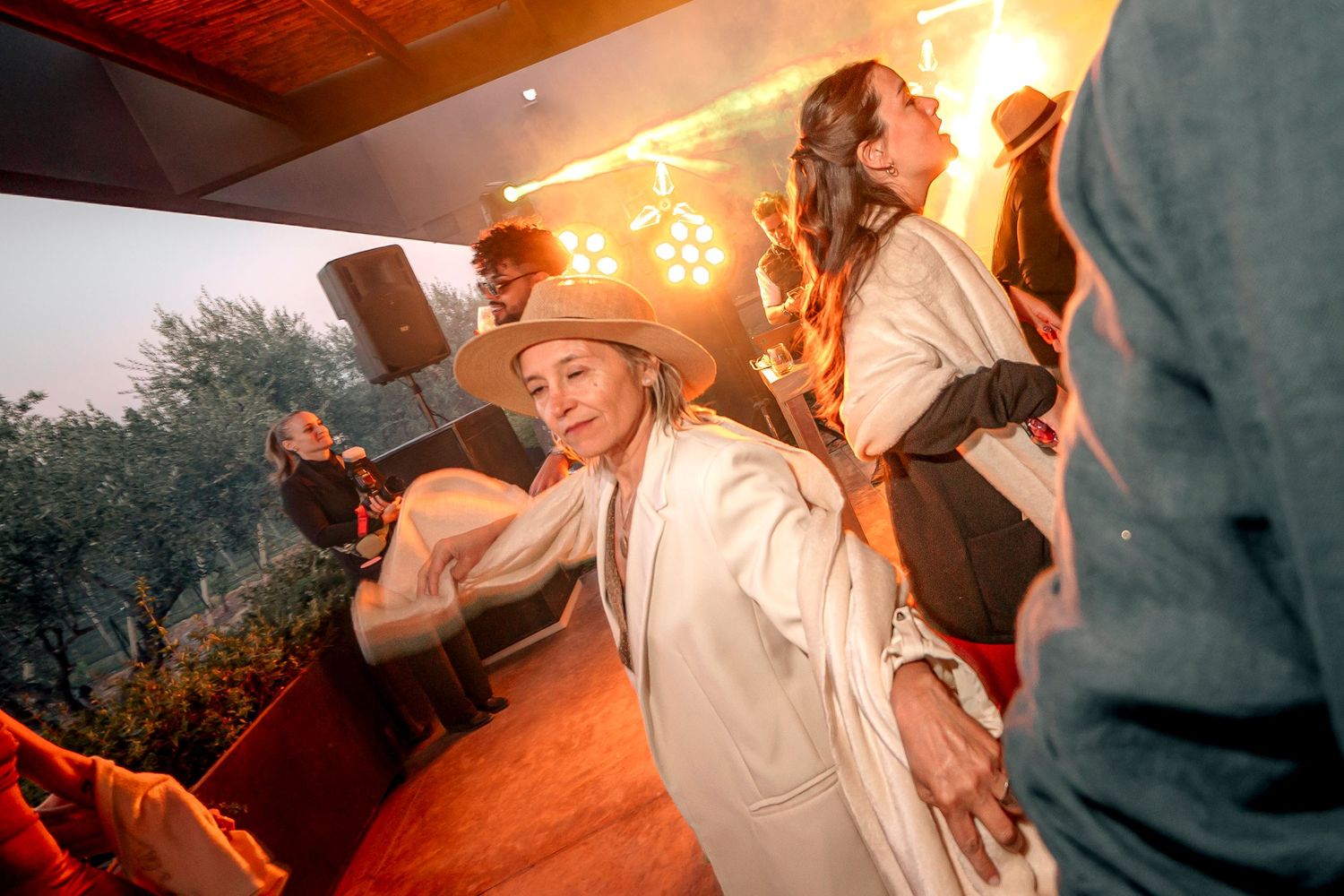 A couple dances together during their first dance at an outdoor wedding reception with string lights overhead.