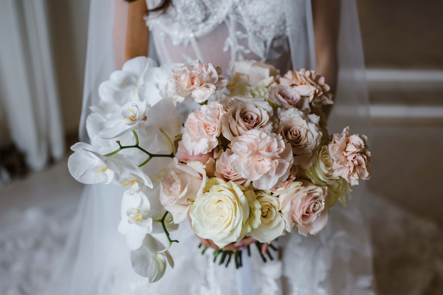 Close-up of a romantic bridal bouquet featuring blush roses, white orchids, and soft pink blooms.