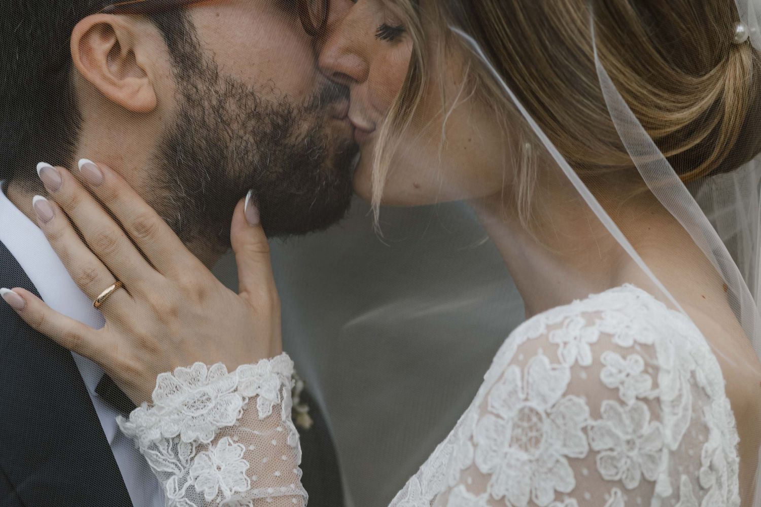 Intimate moment showing hands with wedding rings and delicate lace sleeves.