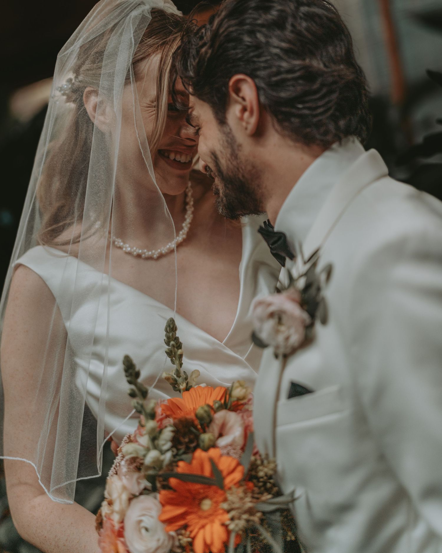 A joyful wedding moment captured with warm lighting and orange florals.